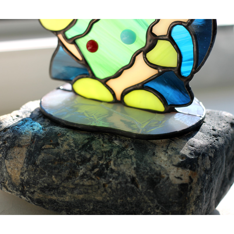 Enlarged-fragment-of-a-white-stand-for-a-stained-glass-suncatcher-of-a-Christmas-gnome-with-a-Christmas-tree-decorated-with-multicolored-balls-The-colored-shado