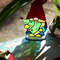 Stained-glass-sun-catcher-Christmas-gnome-with-a-Christmas-tree-in-his-hands-stands-on-a-windowsill-against-the-sunlight-The-sun's-rays-pass-through-the-red-gla