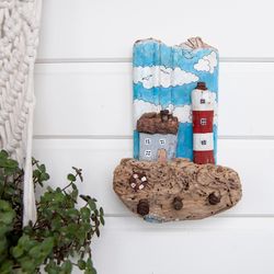 Housekeeper-hanger lighthouse and a house on a beautiful wooden base, an eco-gift made of driftwood in a nautical style