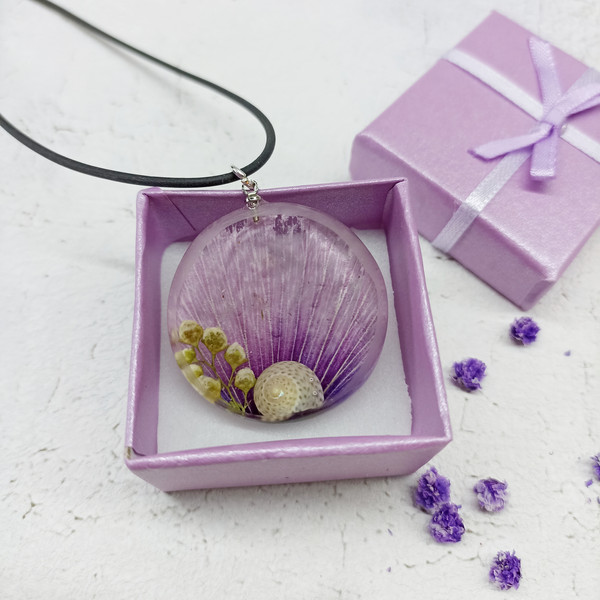 purple necklace with a snail in a box.jpeg