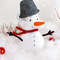 Felt toy snowman with a pail on the head on the background of snow and painted trees