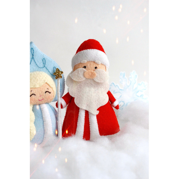 Felt grandfather Frost and Snow maiden toys against the background of snow and snowflakes