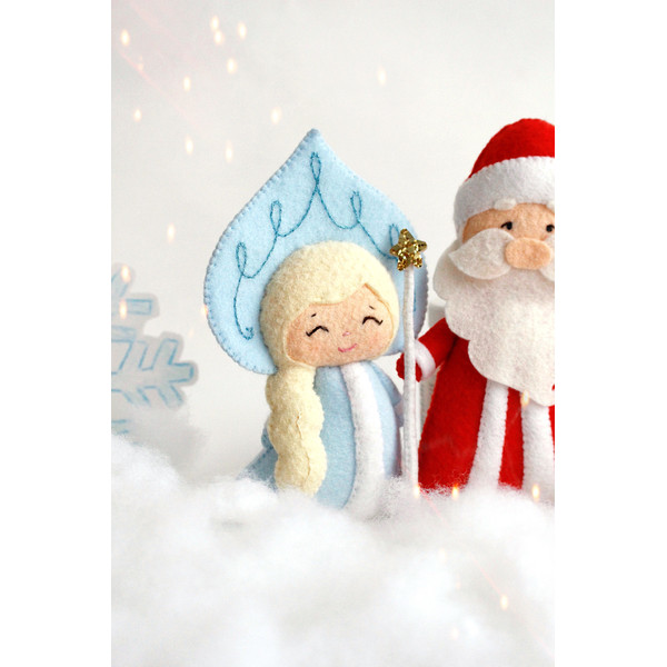 Felt Snow maiden and grandfather Frost toys against the background of snow and snowflakes