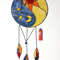 Stained glass Yin Yang dreamcatcher in blue and beige with orange sun and moon next to a red lighter on a white background.jpg