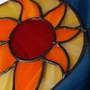 Stained glass depicting orange sun with beige elements with blue glass on the right and solder covered in black patina.jpg