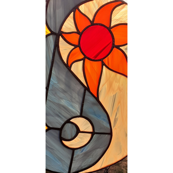 Stained glass depicting sun and moon in a day-night cycle in orange, yellow and blue with solder covered in black patina.jpg