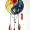 Stained glass Yin Yang dreamcatcher in blue and yellow colors with sun and moon next to a red lighter on a white background.jpg