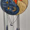 Stained glass Yin Yang suncatcher in art deco style with orange sun and yellow moon symbols in front of a white metal fence.jpg