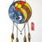 Stained glass dreamcatcher with blue and yellow Yin Yang symbol is lying on a white background near a red lighter.jpg