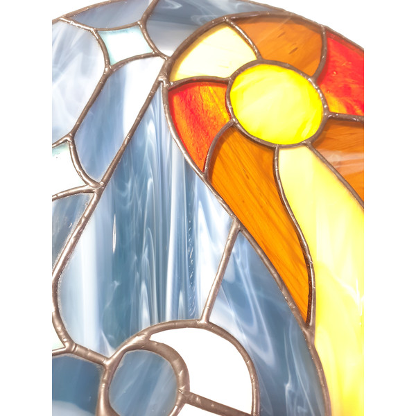 Stained glass depicting day and night in blue, white, yellow, orange and brown colors with soldering covered in black patina.jpg