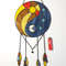 Round stained glass dreamcatcher with blue and yellow Yin Yang symbol is lying on a white background near a red lighter.jpg
