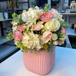 arrangement of artificial flowers in a pink ceramic vase