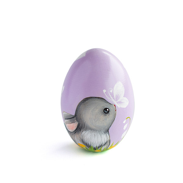 A cute bunny painted on a purple egg with a butterfly on its nose