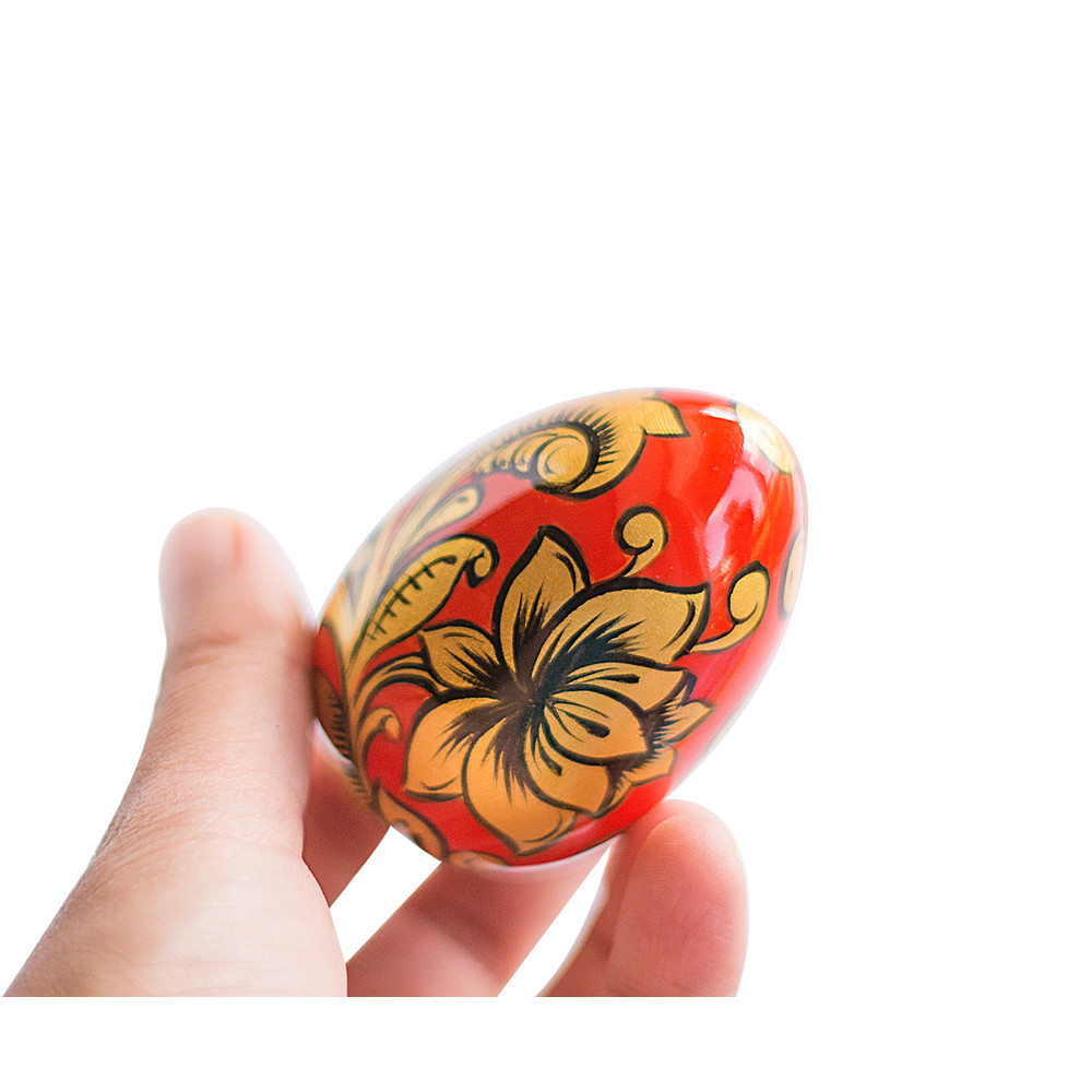 Russian painted egg Khokhloma gold flowers on a red background