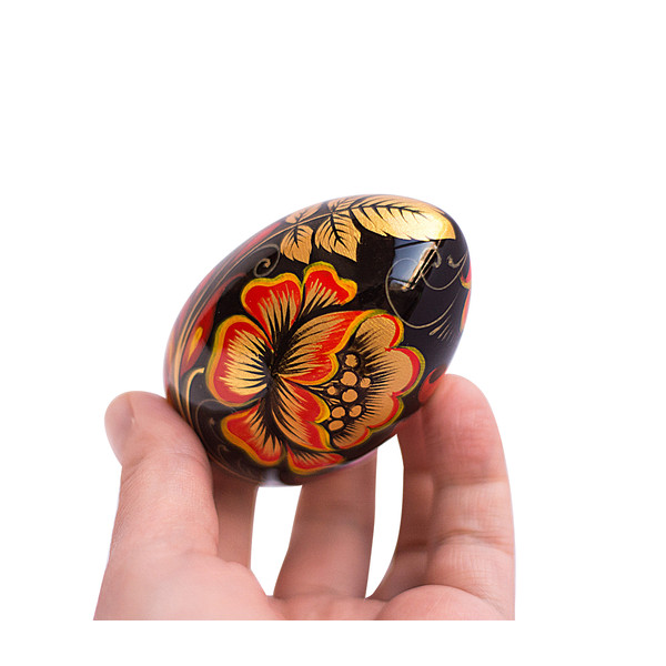 Russian painted egg Khokhloma golden flowers with red leaves on a black background