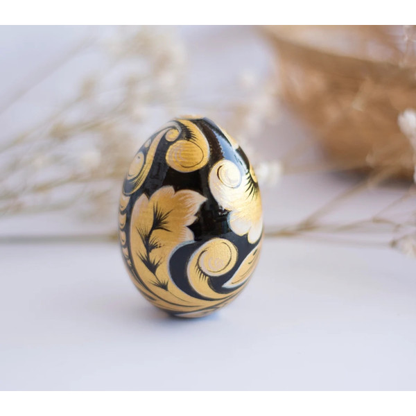 Russian painted wooden egg Khokhloma gold flowers on a black background