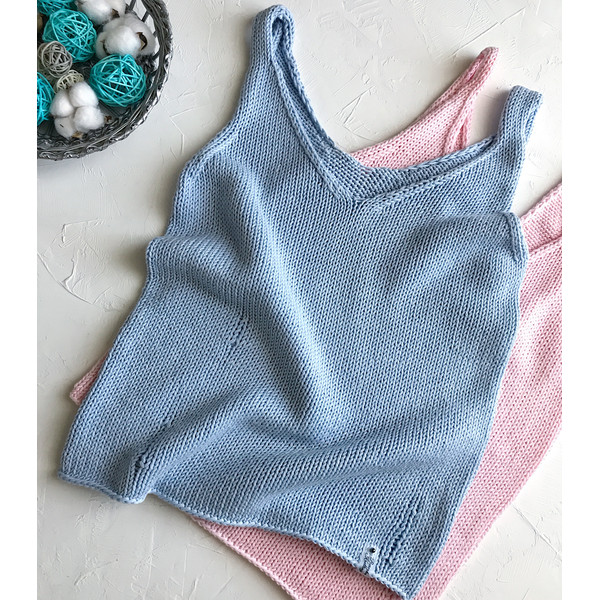 Two hand knitted tops in blue and pink lies on a table.JPG