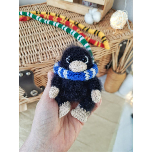 stuffed black niffler toy in slytherin scarf