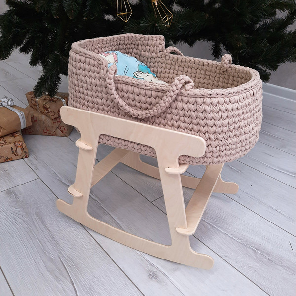Basket for baby dolls in beige handmade on a wooden stand, with a cute bright mattress