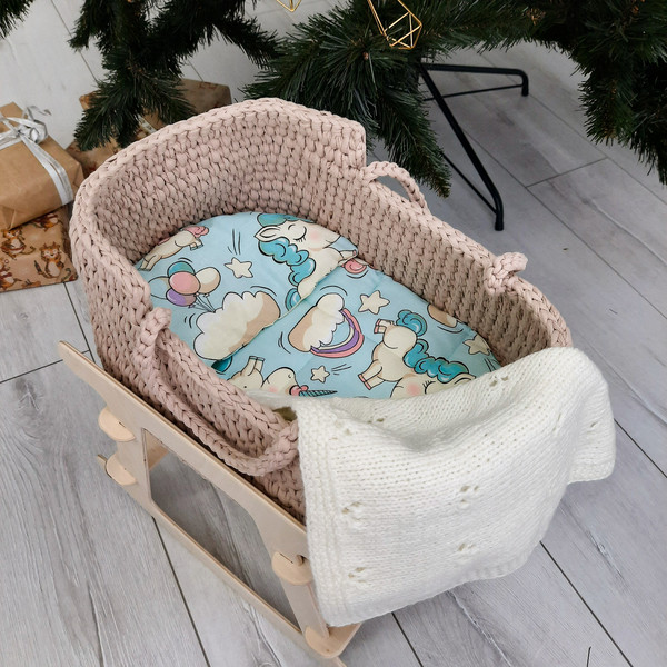 Basket for baby dolls in beige handmade on a wooden stand, with a cute bright mattress and a milk-white blanket