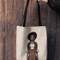 mockup-of-a-woman-s-hand-holding-a-tote-bag-against-a-wooden-background-26693 (14).png
