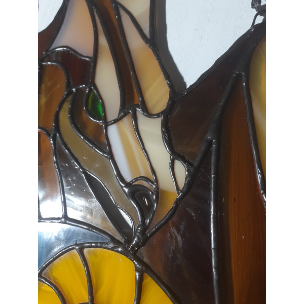 Stained glass depicting a brown dragons head and part of the wing with solder covered in black patina.jpg