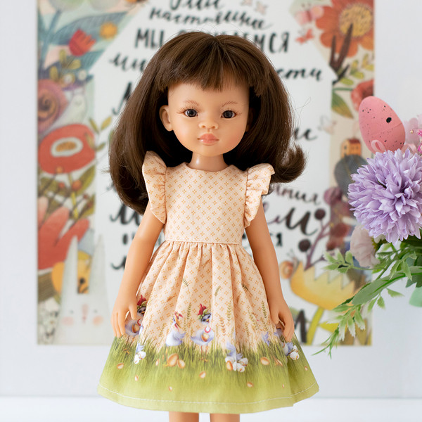 A 13-inch doll in an Easter dress with a print of eggs and chickens
