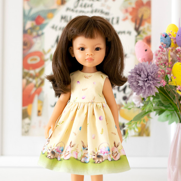 A 13-inch doll in a yellow Easter dress with a print of eggs and Easter bunnies
