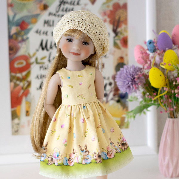 A 14-inch Ruby Red Fashion Friends doll in a yellow Easter dress with a print of Easter bunnies and eggs and an openwork beret.
