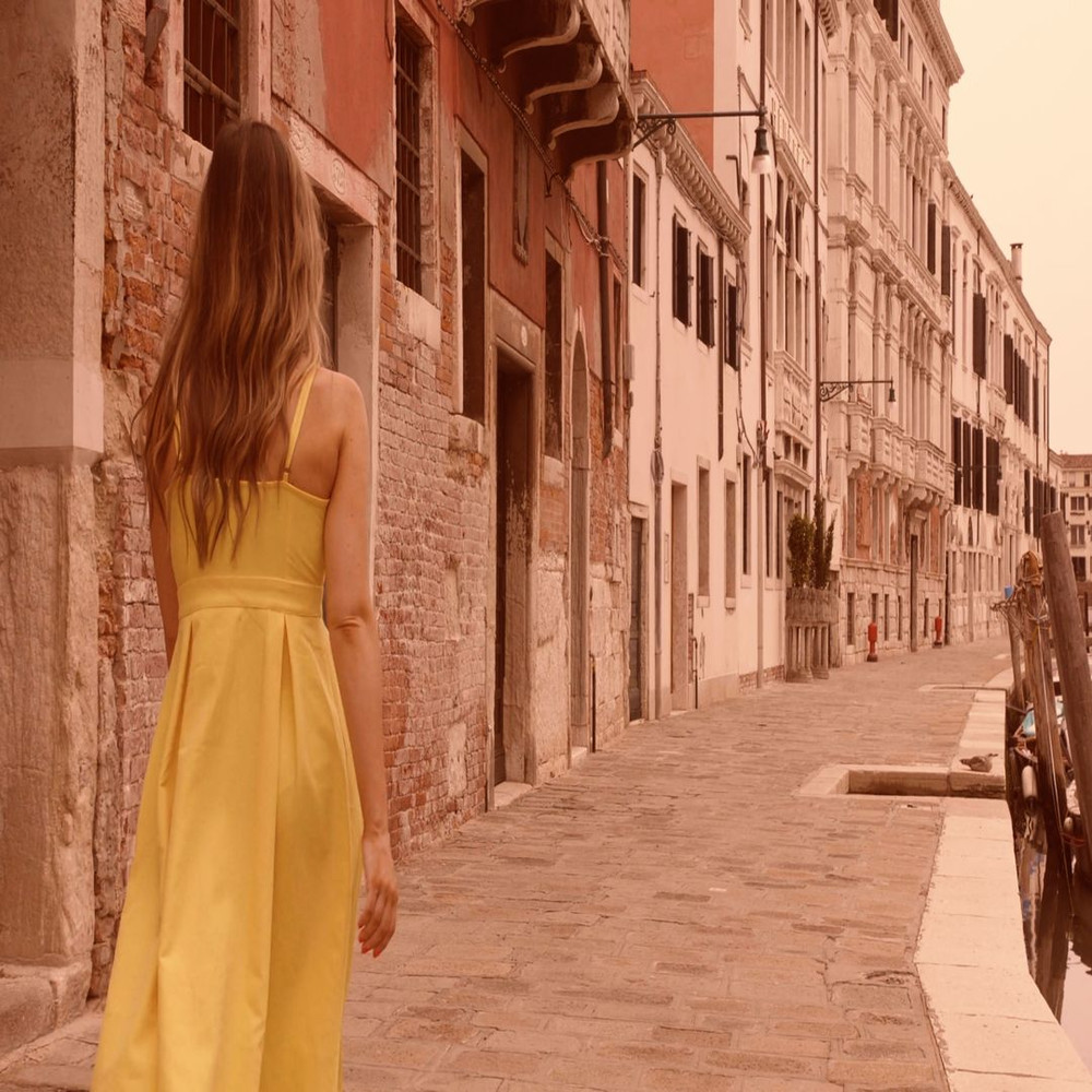 1080x1080 size woman-wearing-a-yellow-dress-and-walking-next-to-a-canal-and-buildings-convert-video-online.com_.00_00_07_24.Quadro001-1594x1062.jpg