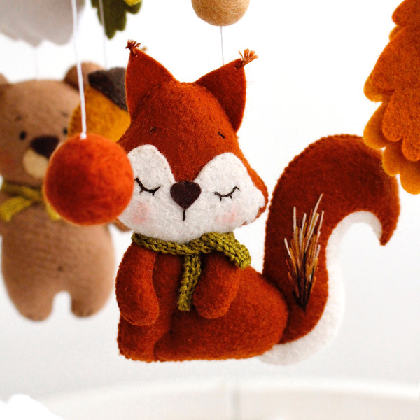 Cute squirrel among leaves, felt balls and forest animals from baby crib mobile