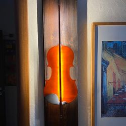 A wall sconce made from an old violin and a bow