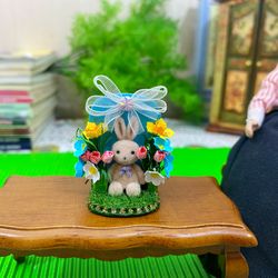 Easter miniature. Bunny on a stand with flowers.