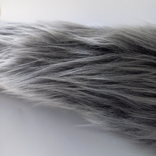 Wolf tail made of faux fur for a party, festival, cosplay, masquerade. Gray-black fluffy tail for fancy dress.