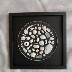 A circle of white shells on a black background. Shells in a frame without glass. Seashell Art. Shell Wall Hanging.
