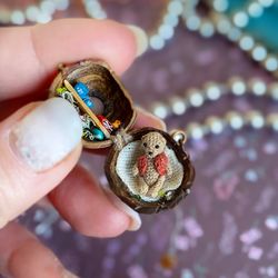 Tiny house in a walnut shell with a miniature teddy bear crocheted inside. Opening pendant