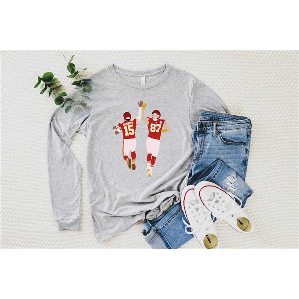 MR-115202314216-mahomes-and-kelci-high-five-long-sleeve-tshirt-chiefs-athletic-heather.jpg