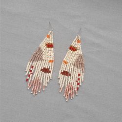 Beige beaded long tassels earrings with an abstract pattern. Boho fringe dangling beadwork earrings Summer beach trend.