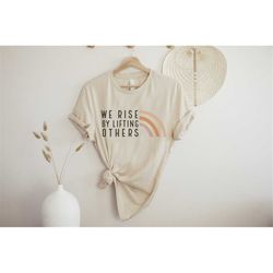 we rise by lifting others graphic tee