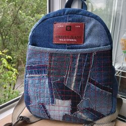 stylish handmade denim backpack with a deep pocket in the front in the lazy boro patchwork style and lined with red plai