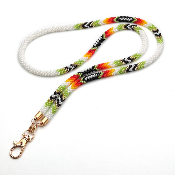A close-up photo of a green ethnic lanyard kit displaying the texture of the crochet stitches and the vibrant hues of the beads.