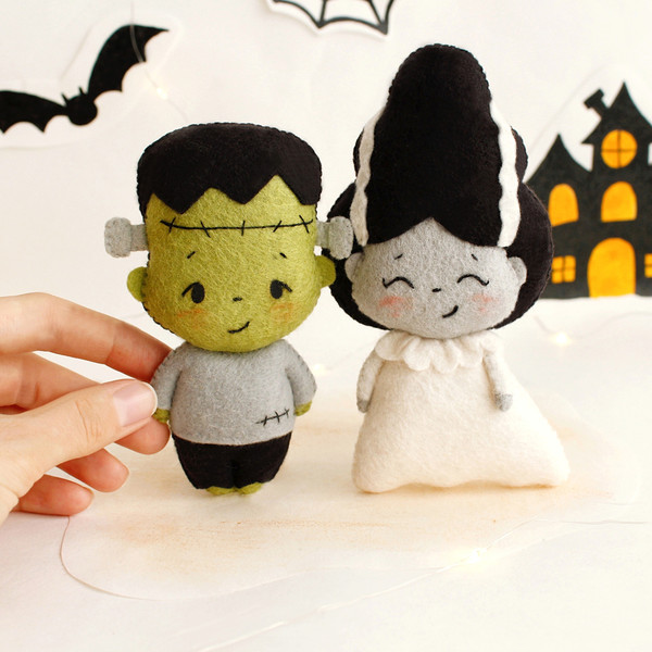 Felt toys Frankenstein and his bride in front of the painted Halloween decor, front view
