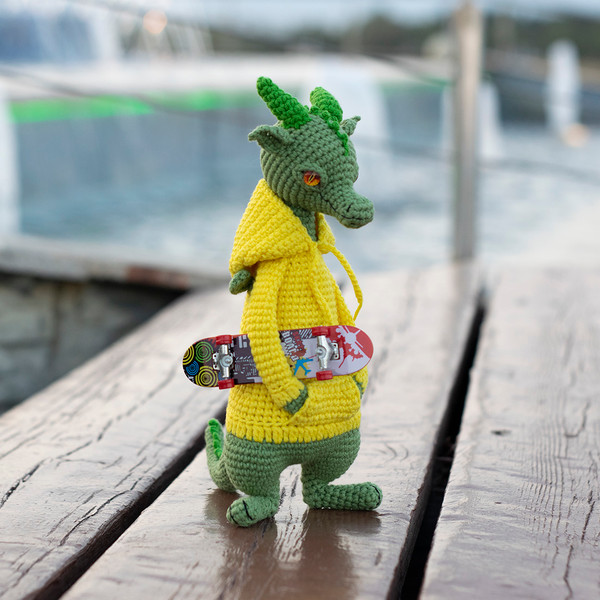 Knitted toy green dragon in hoodie and with skateboard