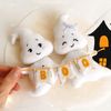 Felt ghost boy and girl with BOO garland laying in the author's hand against the background of painted Halloween decorations, top view