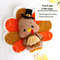 Felt Thanksgiving turkey with pie in the wings laying against the background of painted autumn leaves, front view