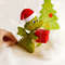 Felt green dragon in Santa cap with red gift box with Christmas presents in his hands near the painted Christmas tree