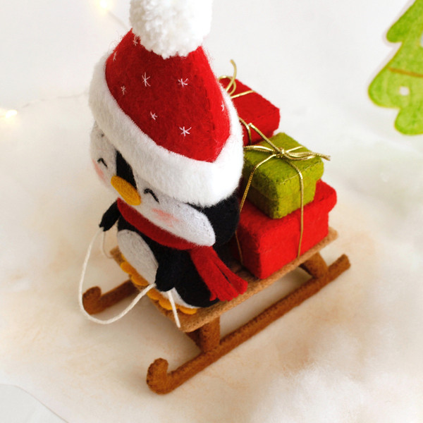 Felt penguin on the sleigh with Christmas presents, top view