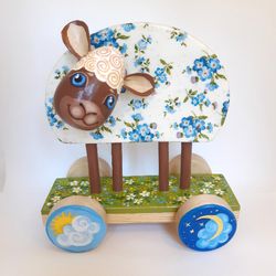 Easter lamb is a vintage-style toy on wheels . The decor is a lamb with a floral pattern . Lamb with forget-me-nots