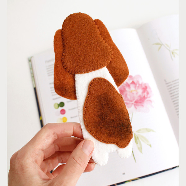 DIY felt hand sewn craft - kids long Basset hound in glasses bookmark in authors hand in front of the opened book, back view