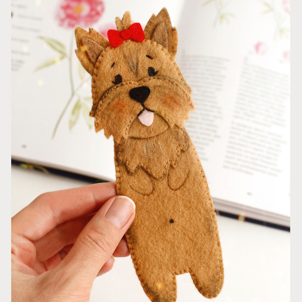 DIY felt hand sewn craft - kids long Yorkshire terrier dog hound bookmark in authors hand in front of the opened book